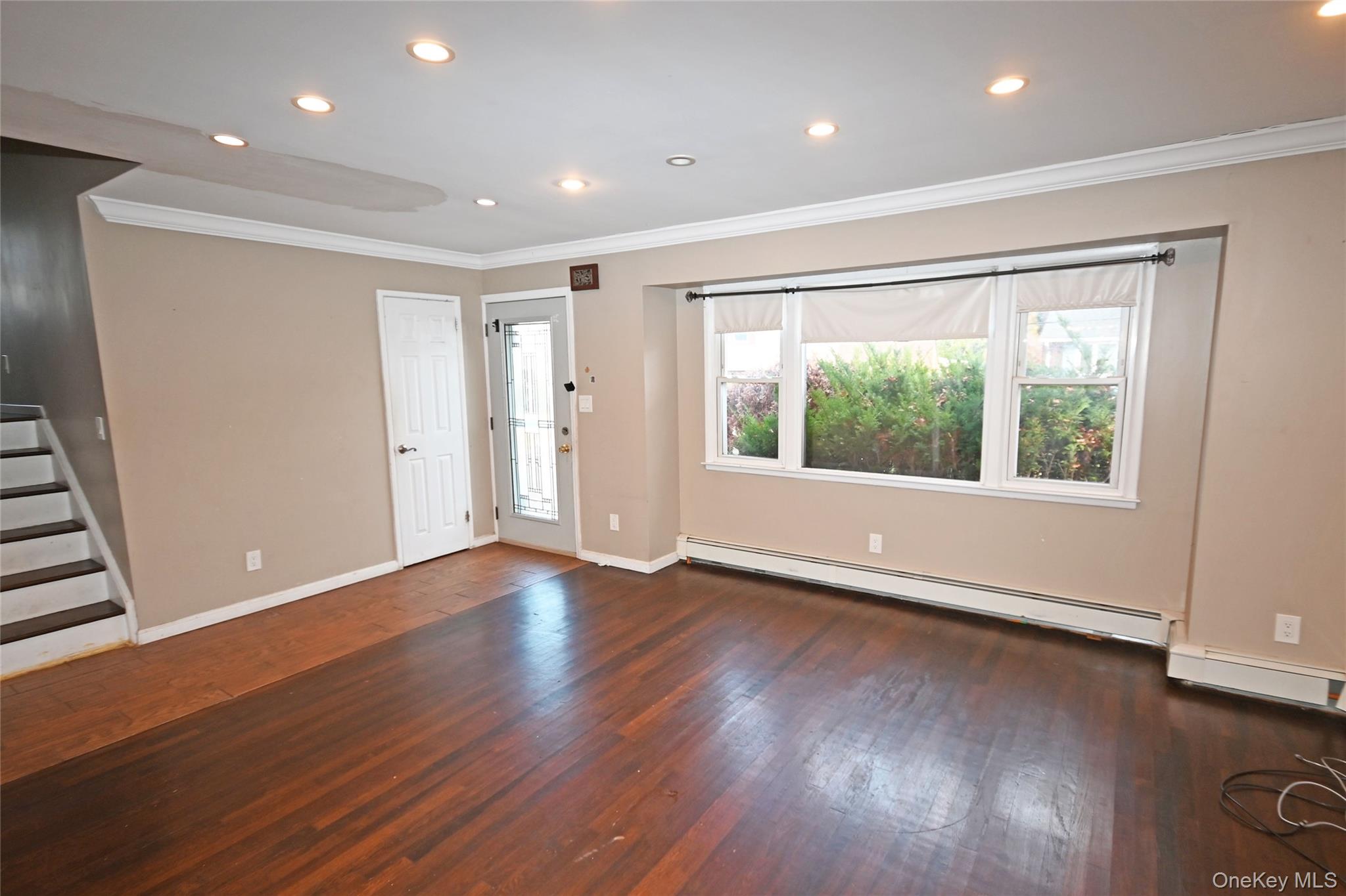 89 Osborne Road West Hempstead, NY 11552 - Photo 21 of 50 Unfurnished living room featuring crown molding, dark wood-type flooring, recessed lighting, a baseboard radiator, and stairway