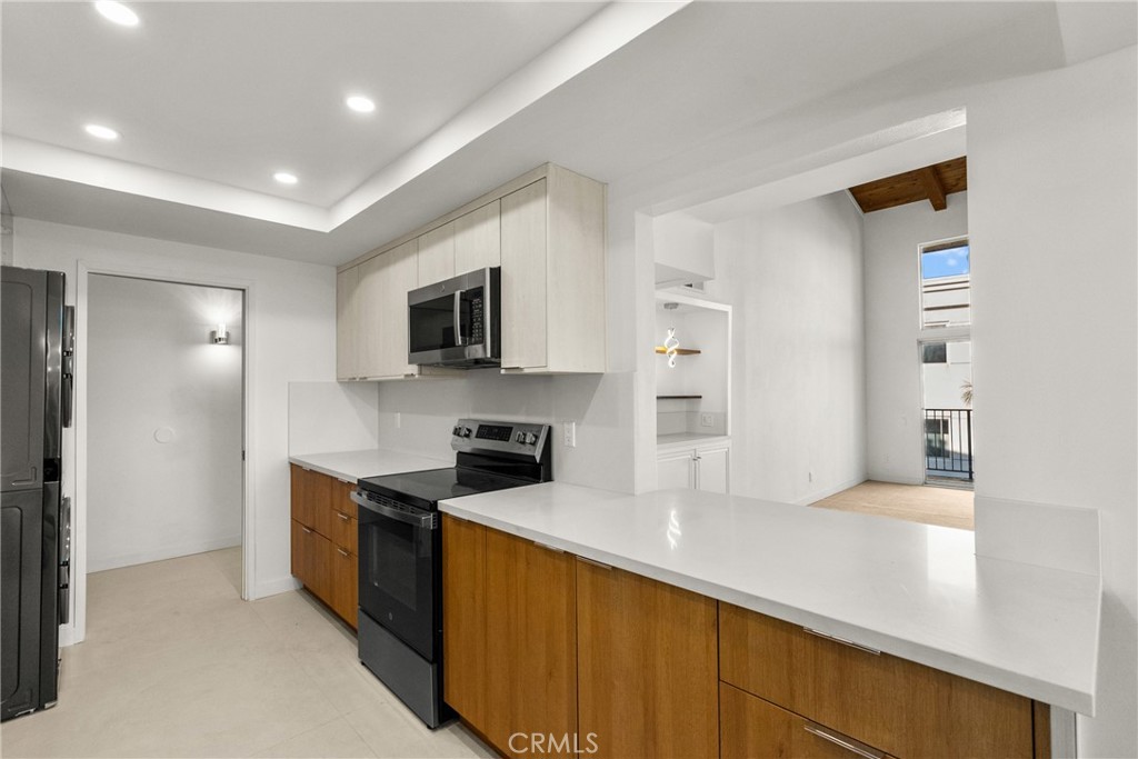 2385 Roscomare Road, Unit F16 Los Angeles, CA 90077 - Photo 7 of 40 a kitchen with stainless steel appliances a refrigerator stove and microwave