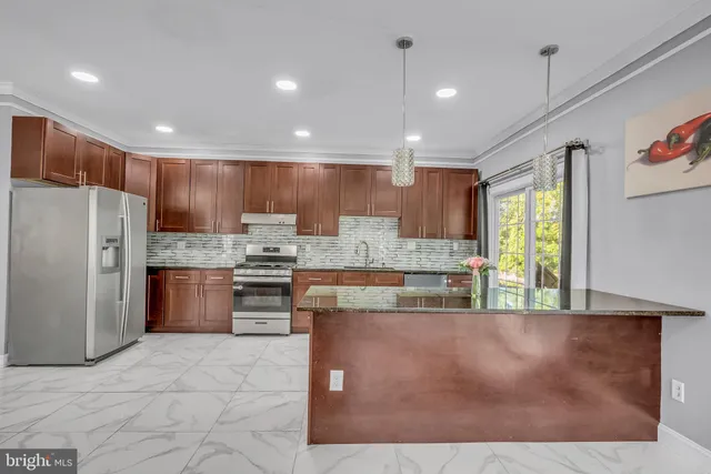 a large kitchen with kitchen island a large counter top stainless steel appliances and cabinets