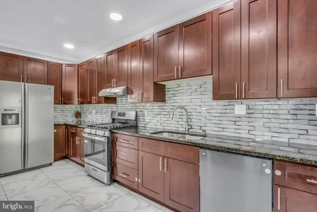a kitchen with stainless steel appliances granite countertop wooden cabinets a refrigerator and a sink