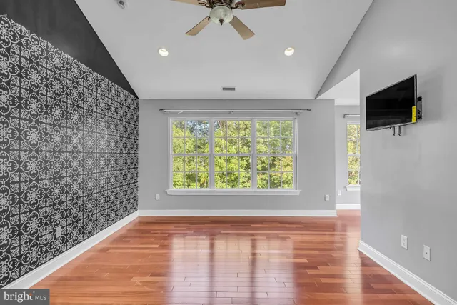 a view of an empty room and a window with wooden floor