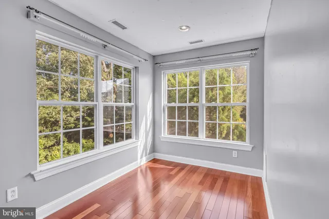 a view of an empty room with a window and wooden floor