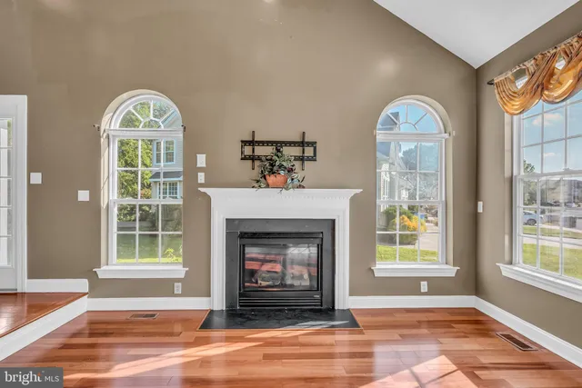 a view of an empty room with wooden floor fireplace and a window