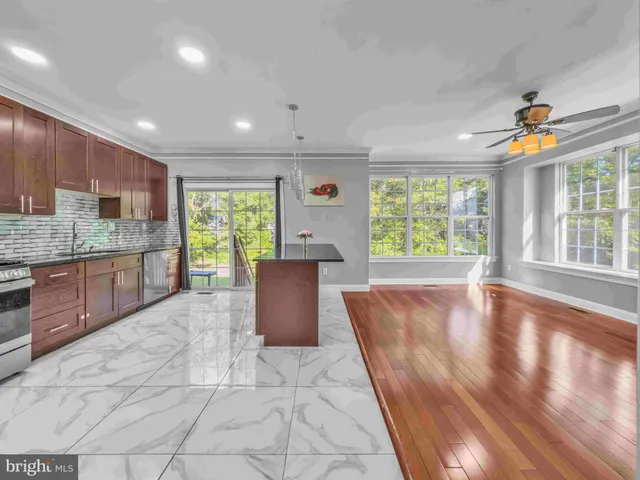 a large kitchen with stainless steel appliances granite countertop a refrigerator a sink dishwasher a stove and a dining table with wooden floor