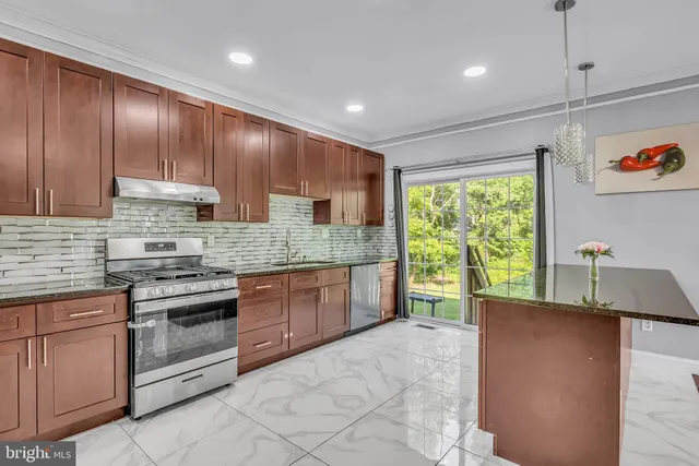 a kitchen with kitchen island granite countertop wooden cabinets a stove a sink and a large window