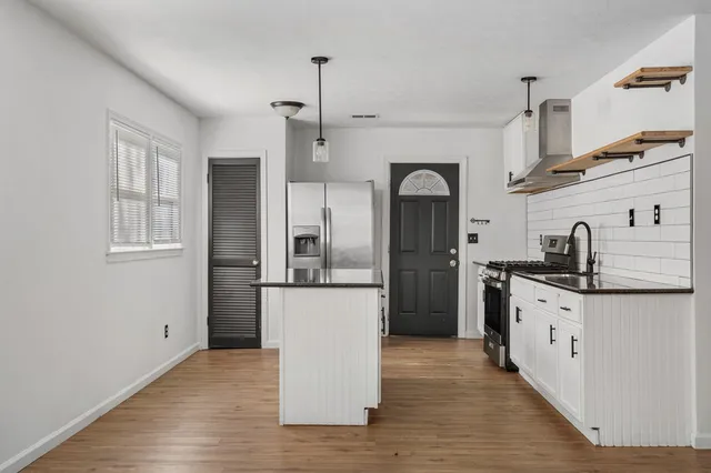 a kitchen with stainless steel appliances granite countertop a refrigerator a sink dishwasher a stove and white countertops with wooden floor