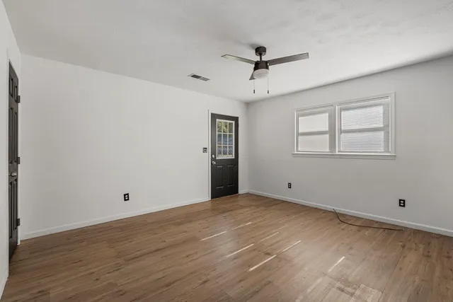 a view of an empty room with wooden floor and a window