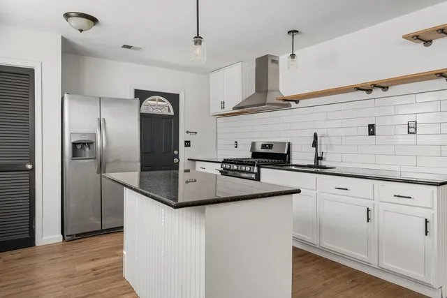 a kitchen with stainless steel appliances granite countertop a sink a refrigerator and wooden floor