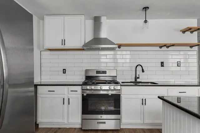a kitchen with granite countertop white cabinets and appliances