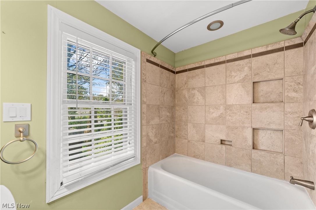 3806 Westwood Road University Heights, OH 44118 - Photo 24 of 41 Bathtub with neutral-toned tiled surround, featuring multiple recessed niches and a brushed nickel showerhead and fixtures
