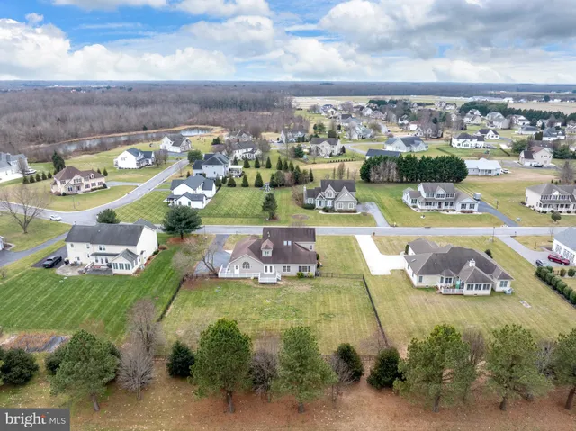 a view of a white house next to a yard with big trees