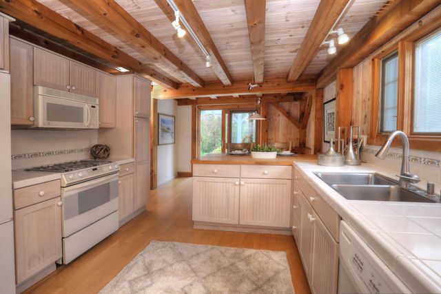 a kitchen with stainless steel appliances granite countertop a sink a stove and a wooden floors