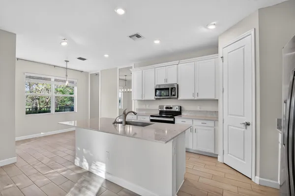 a kitchen with stainless steel appliances a stove a sink a refrigerator and white cabinets with wooden floor