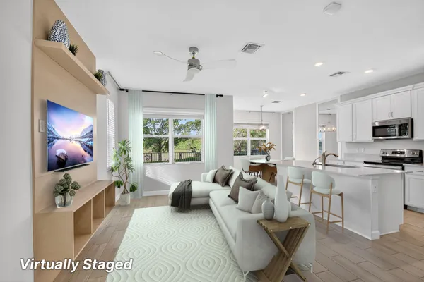 a living room with furniture a flat screen tv and kitchen view