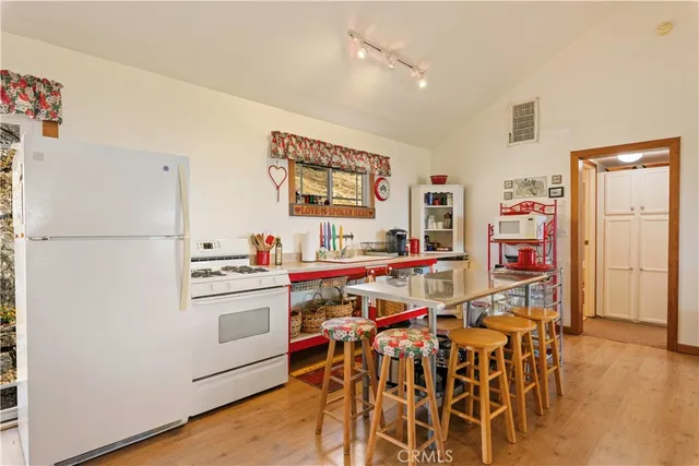 a very nice looking room with a dining table chairs wooden floor and cabinets