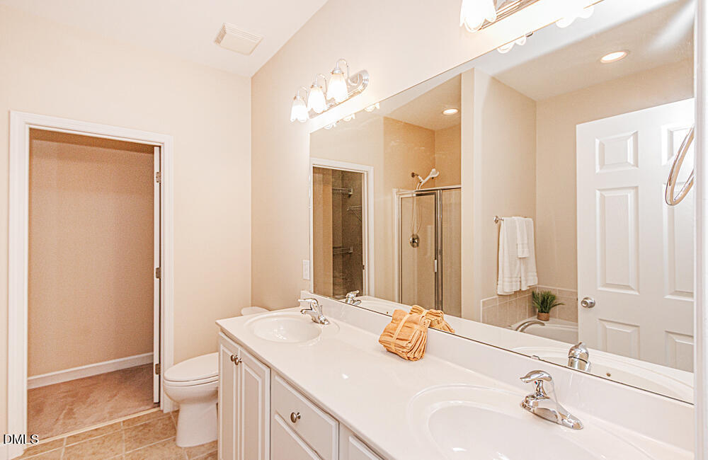 6016 Four Townes Lane Raleigh, NC 27616 - Photo 17 of 32 a bathroom with a double vanity sink toilet and a mirror