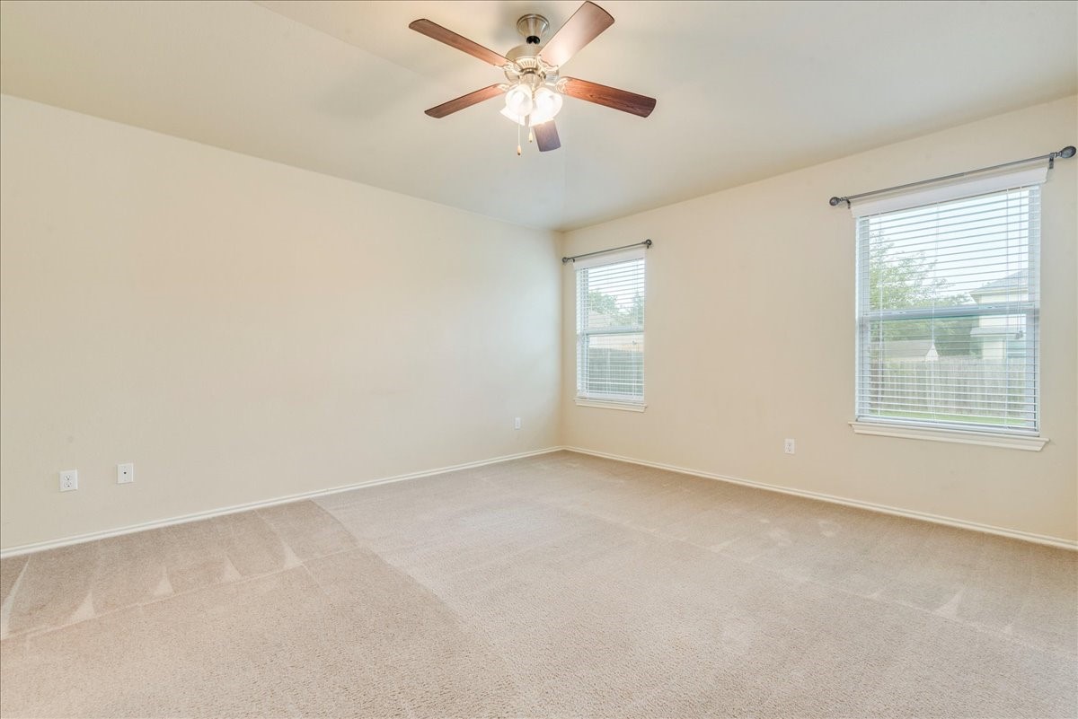 1061 Violet Lane Kyle, TX 78640 - Photo 11 of 34 Spacious primary room with carpeted flooring, ceiling light/fan and natural light windows