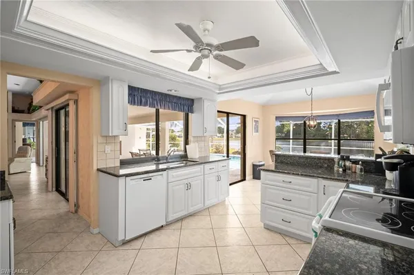 a large white kitchen with a large window a sink and stainless steel appliances