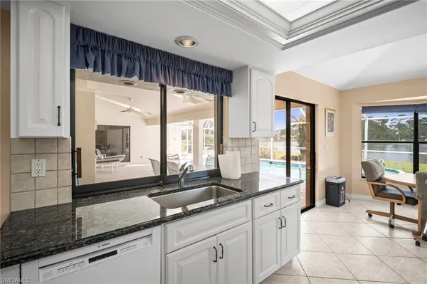 a large white kitchen with a large window and stainless steel appliances