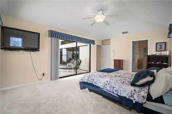 a bedroom with a large bed a flat tv screen and a chandelier