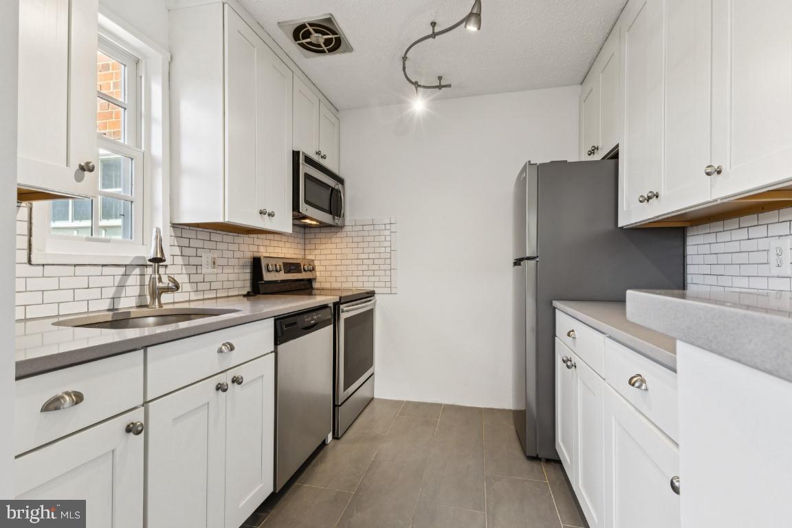 1620 West Abingdon Drive, Unit 301 Alexandria, VA 22314 - Photo 5 of 24 a kitchen with white cabinets and white appliances