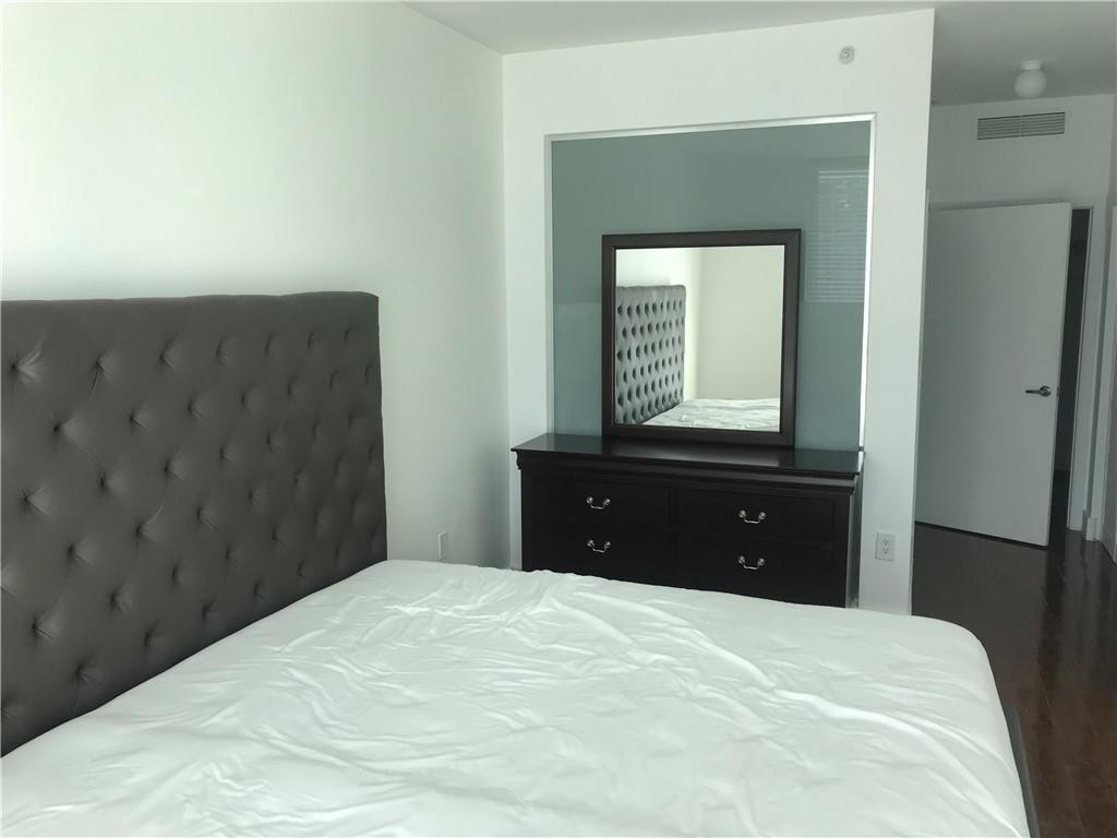 90 Southwest 3rd Street, Unit 1802 Miami, FL 33130 - Photo 12 of 50 a bedroom with a bed and a mirror
