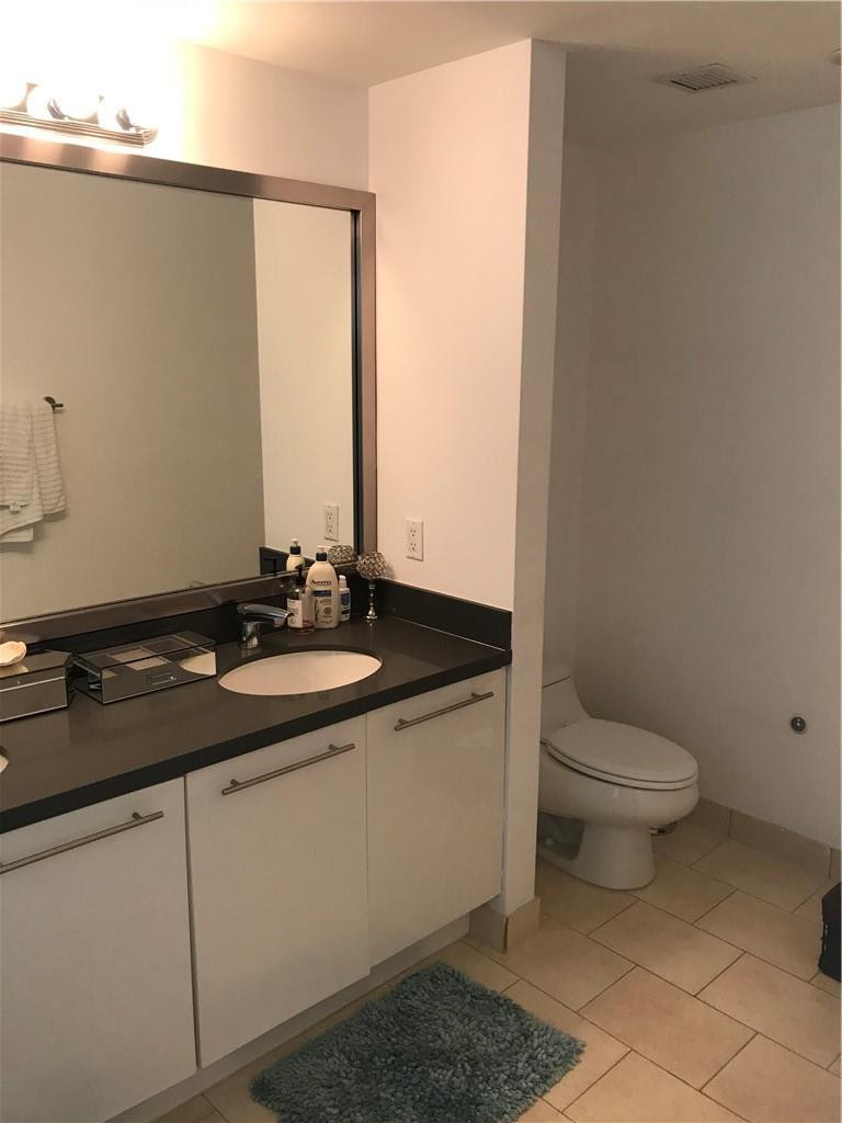 90 Southwest 3rd Street, Unit 1802 Miami, FL 33130 - Photo 14 of 50 a bathroom with a granite countertop sink a toilet and a mirror