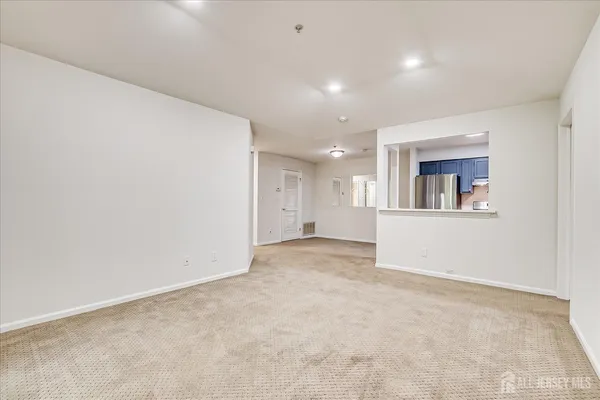 an empty room with a white wall and a refrigerator