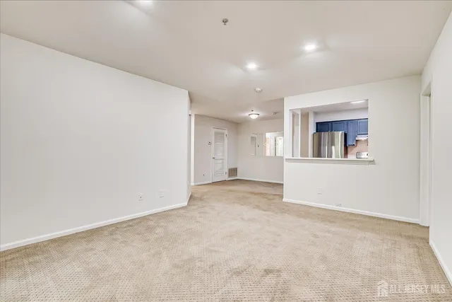 an empty room with a white wall and a refrigerator