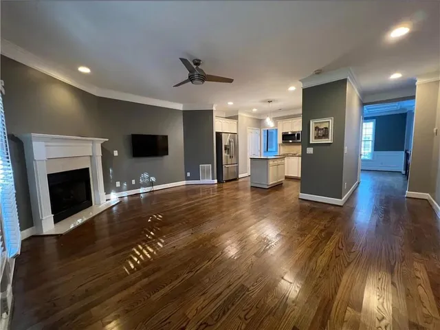 a view of a living room and a kitchen with wooden floor