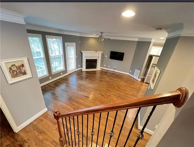 a view of an empty room with wooden floor and windows