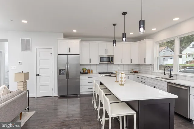 a large kitchen with cabinets chairs and wooden floor