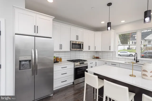 a kitchen with stainless steel appliances kitchen island a sink a stove a refrigerator and white cabinets