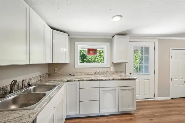 a kitchen with granite countertop a sink cabinets window and stainless steel appliances