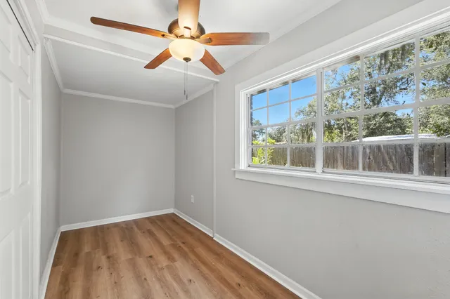 a view of empty room with wooden floor and fan