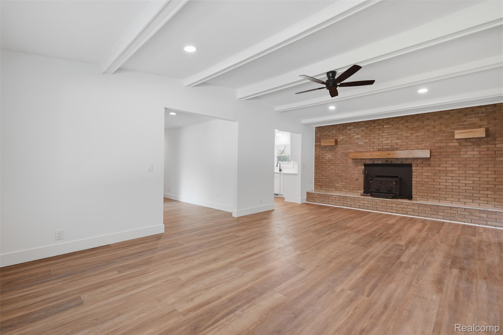 4655 Denton Road Canton, MI 48188 - Photo 12 of 54 Wood-finish flooring, brick-clad fireplace with wood mantel, beamed ceiling with recessed lighting, and a ceiling fan
