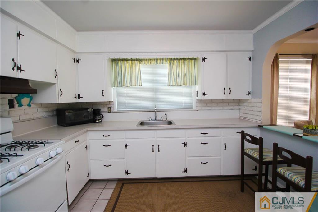 503 Crows Mill Road Fords, NJ 08863 - Photo 6 of 19 a kitchen with granite countertop a sink a stove a window and white cabinets