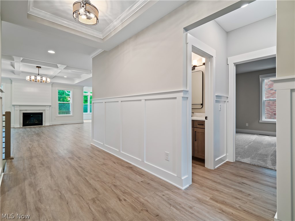 32 Brookside Lane North Ridgeville, OH 44039 - Photo 11 of 50 Hall with light wood-type flooring, a decorative wall, beamed ceiling, coffered ceiling, and a chandelier