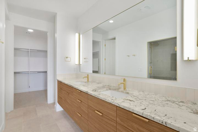 990 Manen Street Washington, UT 84780 - Photo 19 of 43 Spacious bathroom featuring a floating dual vanity with wood-finish cabinetry and light-colored countertops, dual undermount sinks, and gold-finish fixtures