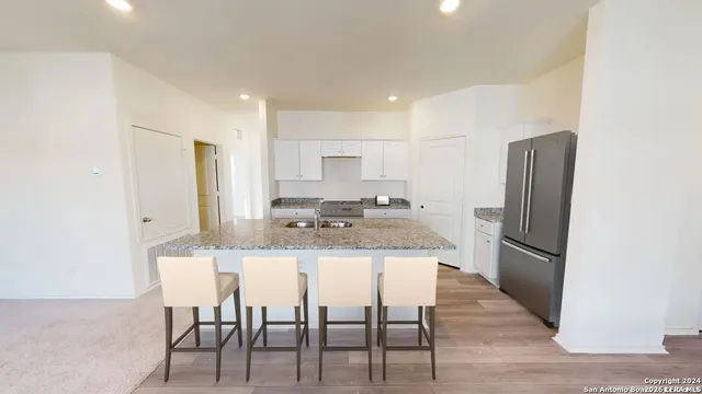a kitchen with stainless steel appliances granite countertop a dining table chairs refrigerator and sink