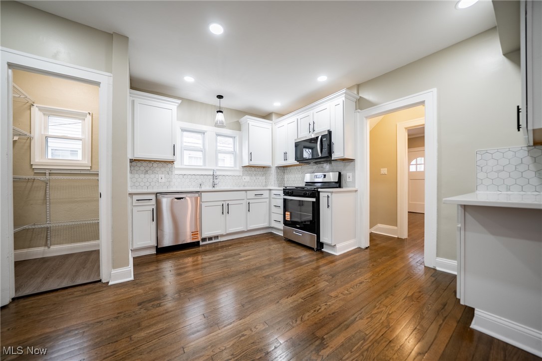 3816 Summit Park Road Cleveland Heights, OH 44121 - Photo 11 of 35 Kitchen with appliances with stainless steel finishes, pendant lighting, white cabinets, dark wood-type flooring, and tasteful backsplash