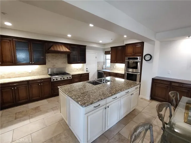 a kitchen with stainless steel appliances kitchen island granite countertop a sink and a refrigerator