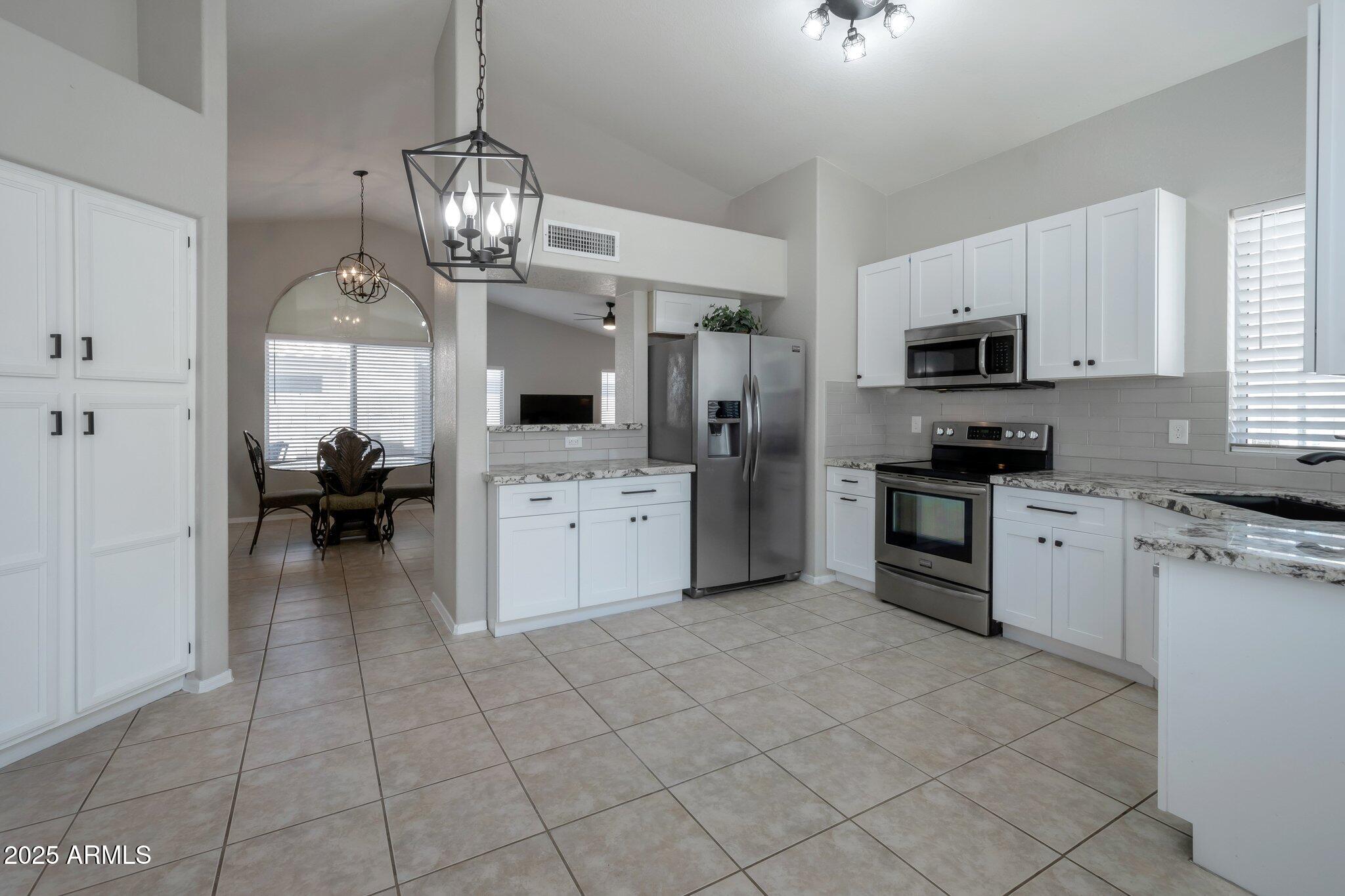 839 West Silver Creek Road Gilbert, AZ 85233 - Photo 2 of 15 a kitchen with kitchen island granite countertop a sink cabinets and stainless steel appliances