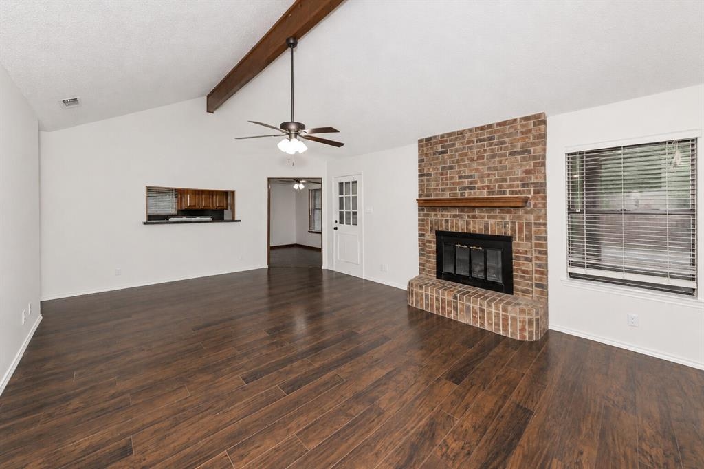 1001 Rosebud Drive Azle, TX 76020 - Photo 9 of 36 Spacious living area featuring wood-finish flooring, a vaulted ceiling with exposed wood beams, and a ceiling fan