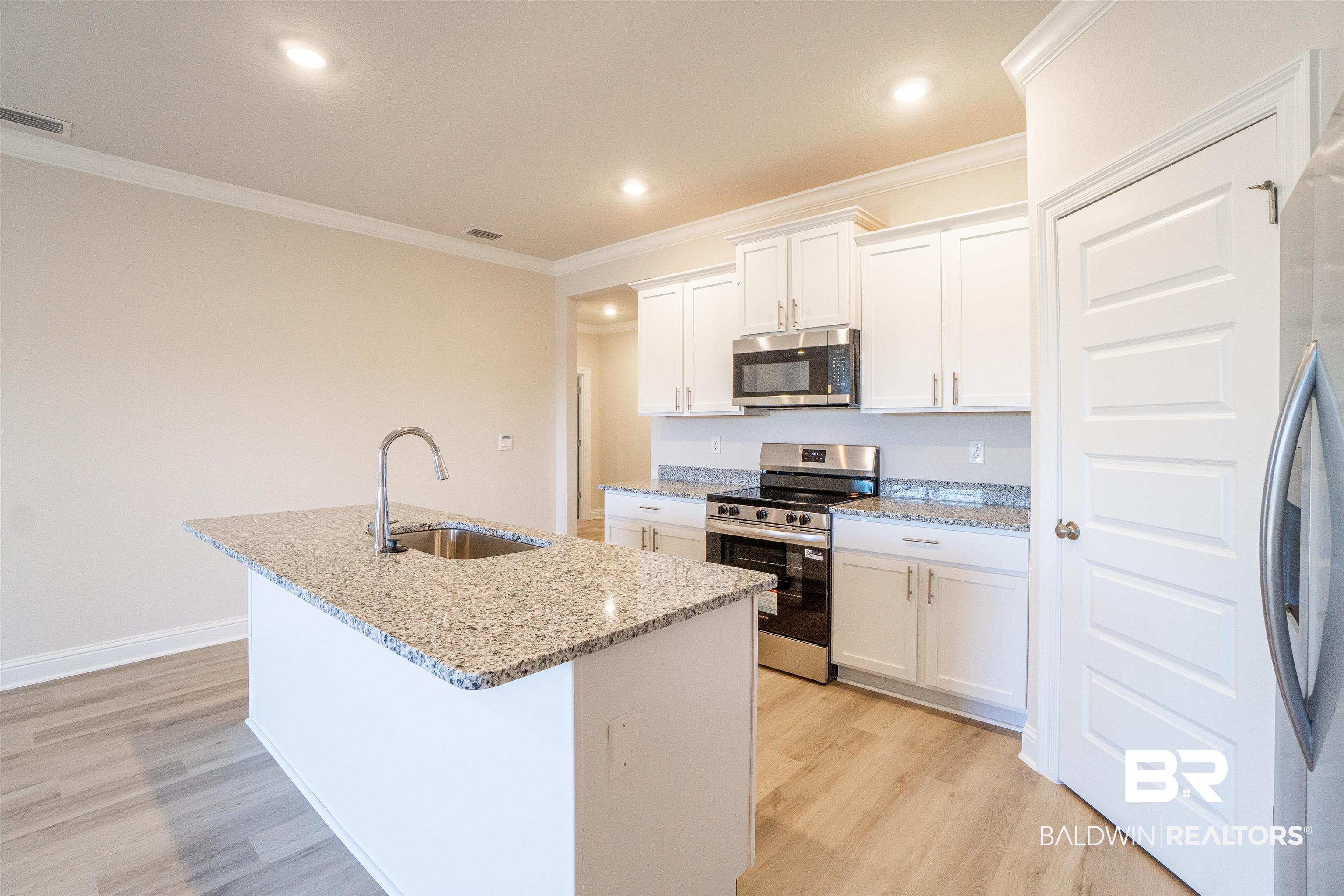 1073 Hayward Loop Foley, AL 36535 - Photo 4 of 18 Modern kitchen featuring a central island with an undermount sink and stone-finish countertop