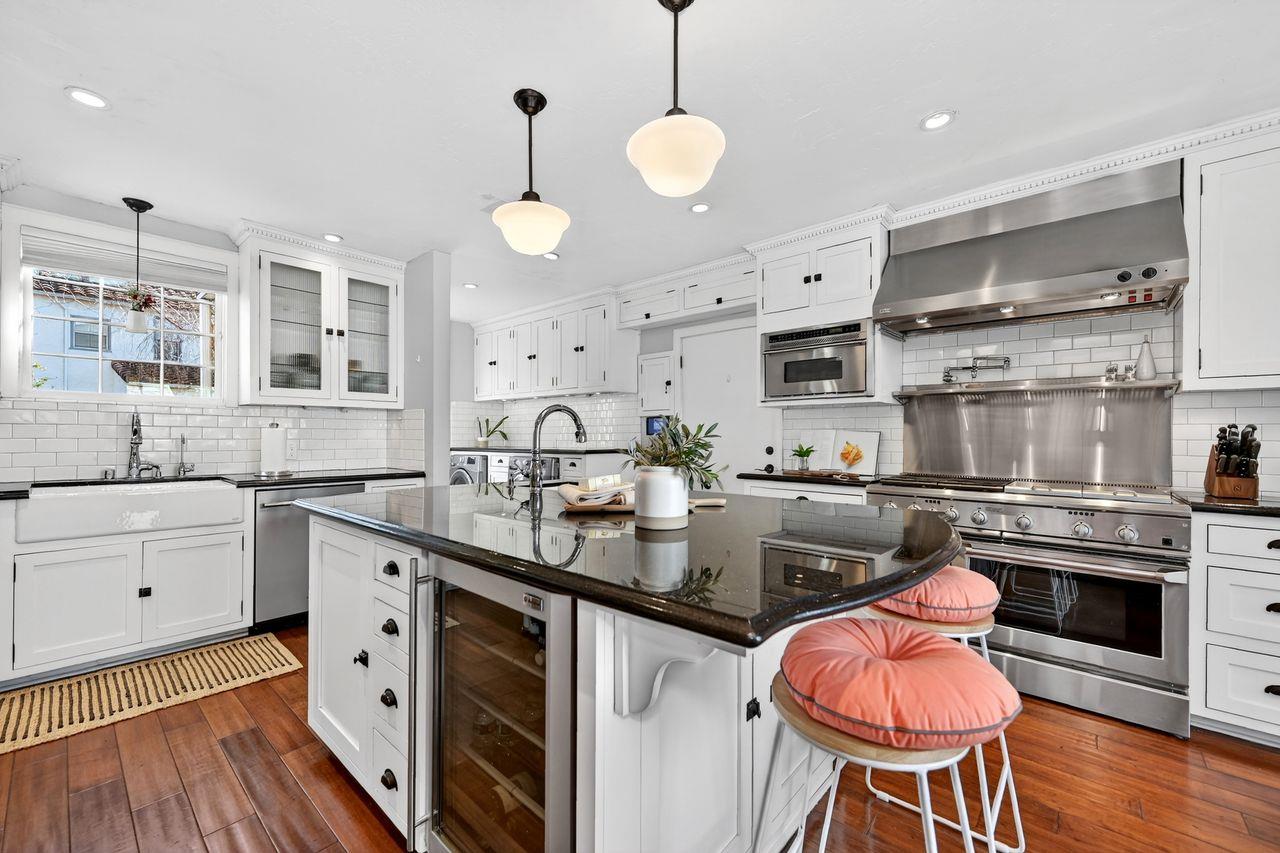 1716 Sutterville Road Sacramento, CA 95822 - Photo 18 of 57 a kitchen with stainless steel appliances a stove a sink and white cabinets with wooden floor