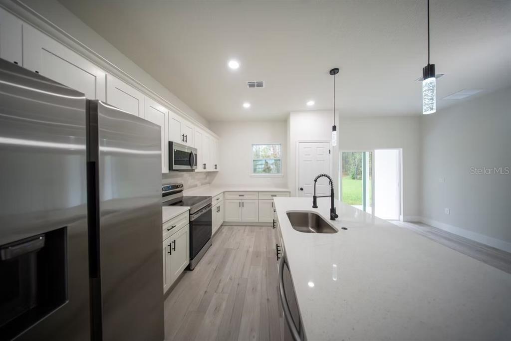 6442 North Sandborn Loop Citrus Springs, FL 34433 - Photo 11 of 33 a kitchen with stainless steel appliances granite countertop a refrigerator a stove and a sink with wooden floor