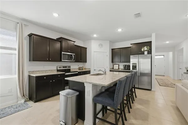 a kitchen with stainless steel appliances granite countertop a stove a sink a microwave a dining table and chairs