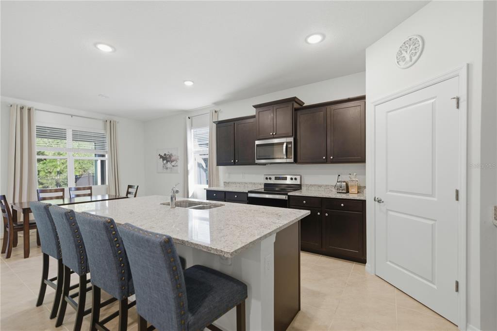 5157 Northwest 43rd Ln Road Ocala, FL 34482 - Photo 7 of 70 a kitchen with stainless steel appliances a stove a sink a microwave a refrigerator white cabinets and wooden floor