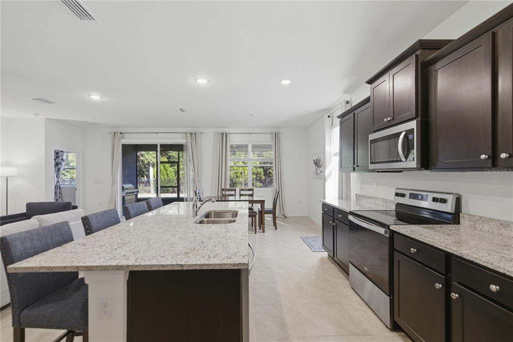 5157 Northwest 43rd Ln Road Ocala, FL 34482 - Photo 8 of 70 a kitchen with stainless steel appliances granite countertop a stove a sink a microwave a dining table and chairs